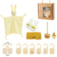 Une collection d'essentiels pour l'hygiène de bébé et d'accessoires dont un doudou BABY PREMA Coffret Cadeau Naissance Bébé, des cartes jalons en bois, une paire de chaussettes avec écrit "reine" sur les semelles, un bandeau jaune.