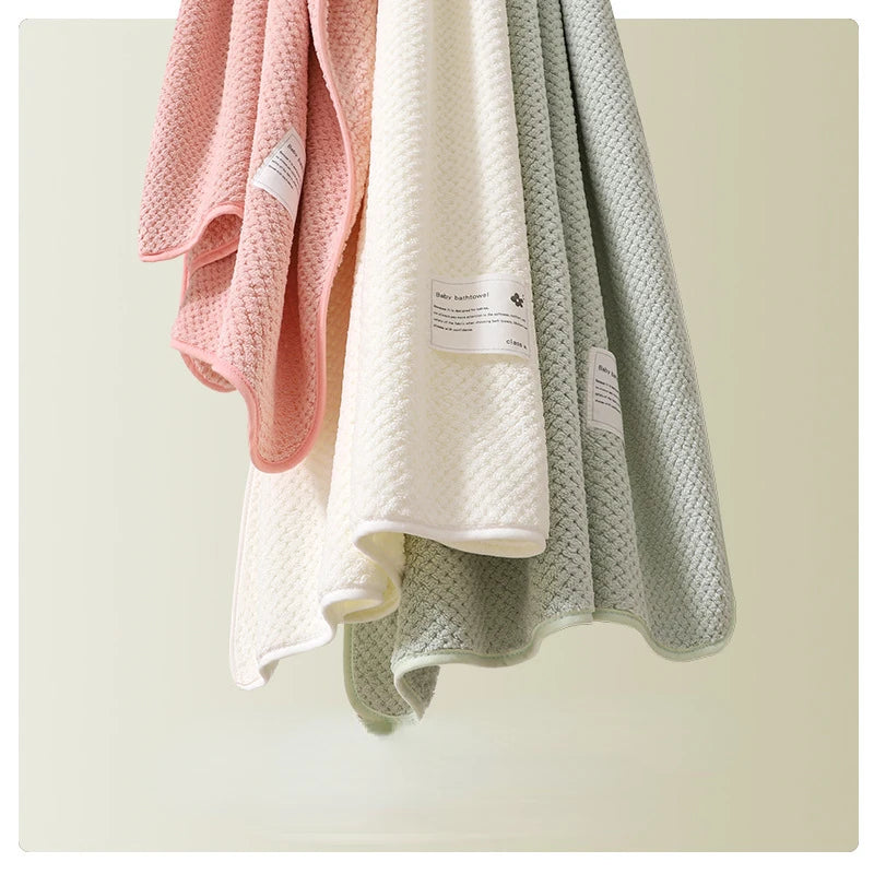 Les serviettes Baby Prema aux tons pastel doux dans des teintes roses, blanches et vertes pendent gracieusement en mettant l'accent sur leurs textures moelleuses et leurs étiquettes de qualité de tissu, parfaites pour un bébé ou un prématuré.