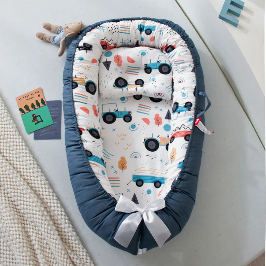 Un Lit de Bébé Portable douillet de BABY-PREMA avec un motif ludique, offrant un espace confortable et sécurisé pour qu'un enfant puisse se reposer, avec des bords doux et rembourrés et un joli nœud en bas.