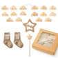 Un coffret BABY PREMA Coffret Cadeau Naissance Bébé composé de nuages en bois marquant les âges de un à douze mois, une paire de chaussettes avec la lettre « n » dessus, un cadre photo étoile en bois, une baguette article bébé en forme d'étoile.