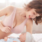 Une femme souriante dans un haut rose regarde tendrement un bébé allongé, suggérant un moment de maternité avec le Soutien d'Allaitement & Maternité de la marque BABY PREMA.