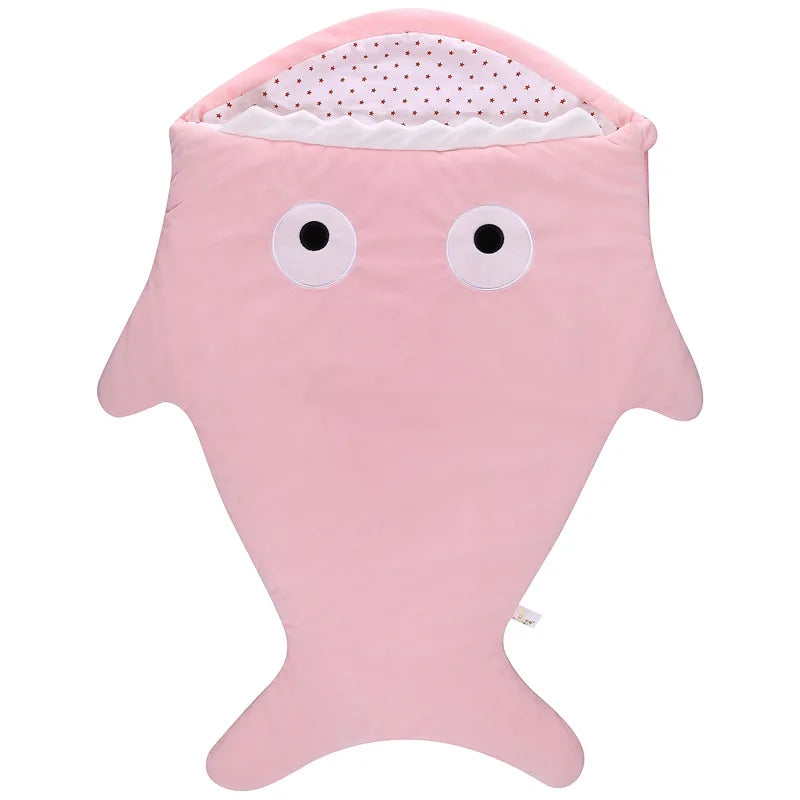 Un article bébé : une couverture en polaire ultra douce et moelleuse rose à thème de requin de la marque BABY PREMA, avec un design fantaisiste offrant une capuche aux yeux cartoon et un intérieur à pois.