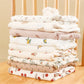 Une pile soignée de couverture Emmaillotage Baby PREMA fraîchement lavée et pliée en coton pour Bébé avec de jolis imprimés disposés sur une surface en bois, indispensables à l'hygiène de bébé.