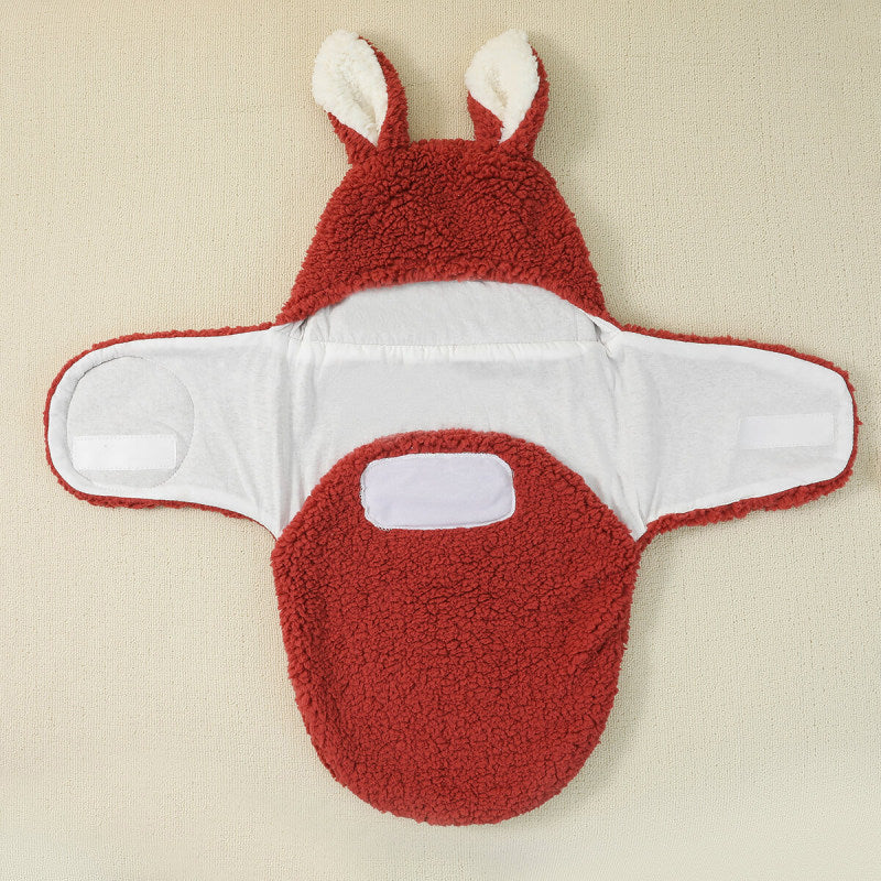 Un Cocon Couverture bébé - Baby Prema rouge et blanc conçu pour ressembler à un adorable lapin, avec des oreilles duveteuses et un devant texturé, posé à plat sur BABY PREMA