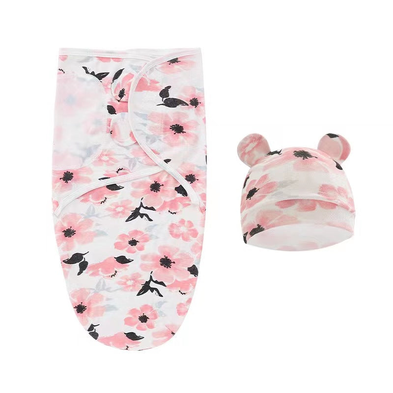 Un adorable ensemble d'emmaillotage et de chapeau pour bébé Baby Prema avec un motif imprimé floral rose et colibri noir, avec de jolies petites oreilles sur le chapeau, parfait pour un enfant prématuré.