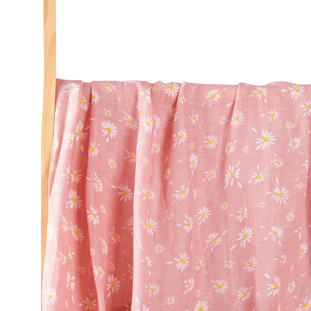 Couverture Lange d'Emmaillotage rose avec un motif de marguerites accrochée à une tige en bois sur fond blanc, idéale pour la chambre de bébé de BABY PREMA.