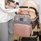 Une personne attachant un élégant sac à langer Sac à Langer Bébé Marron avec USB à la poignée d'une petite poussette BABY PREMA.