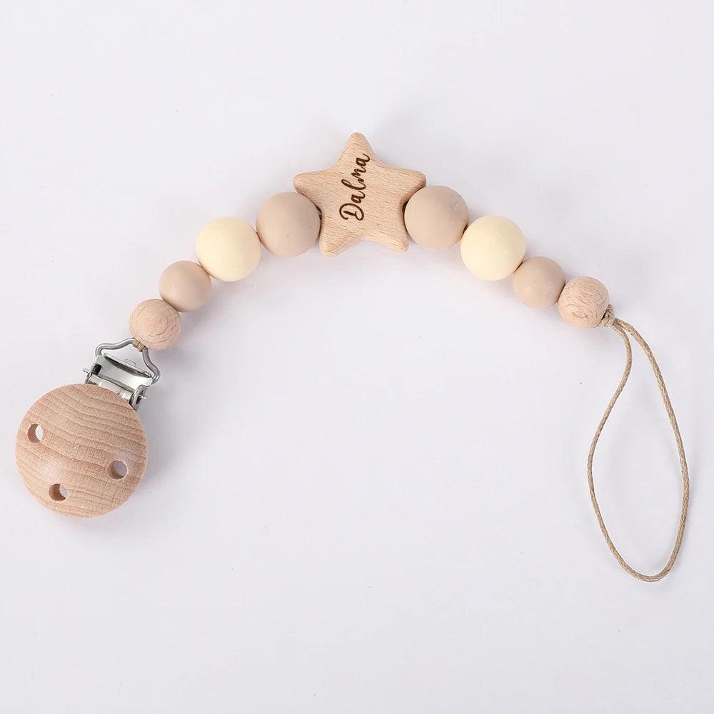 Un article bébé : un Attache Sucette Bébé Personnalisé en bois de la marque BABY-PREMA avec le prénom "Darina" gravé sur une perle en forme d'étoile.