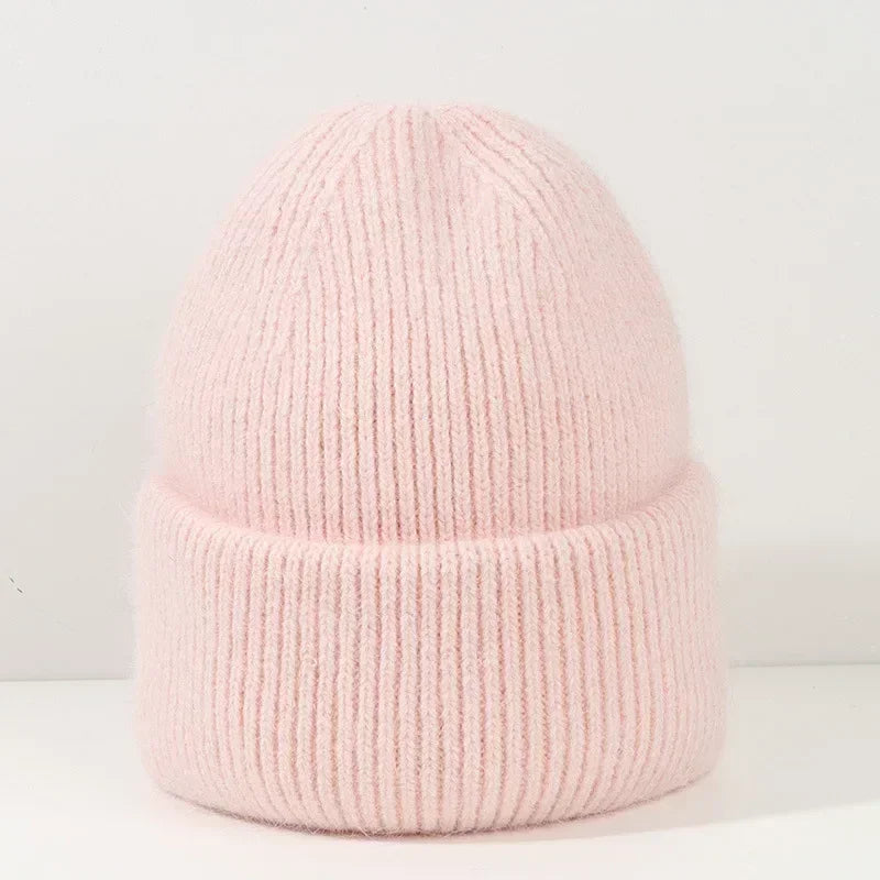 Une douce Bonnet Angora Pour Maman en tricot tricoté rose pâle conçu comme accessoire bébé, avec un revers plié présenté sur un fond neutre de la marque BABY PREMA.