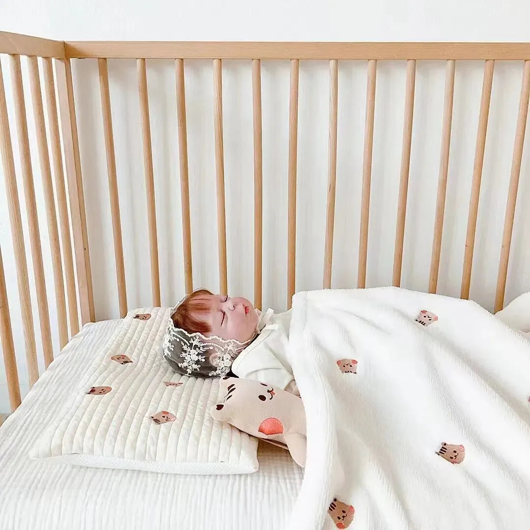 Un bébé paisible qui dort paisiblement dans un berceau avec une couverture bébé en polaire corail BABY PREMA et les produits d'hygiène nécessaires pour bébé à proximité.