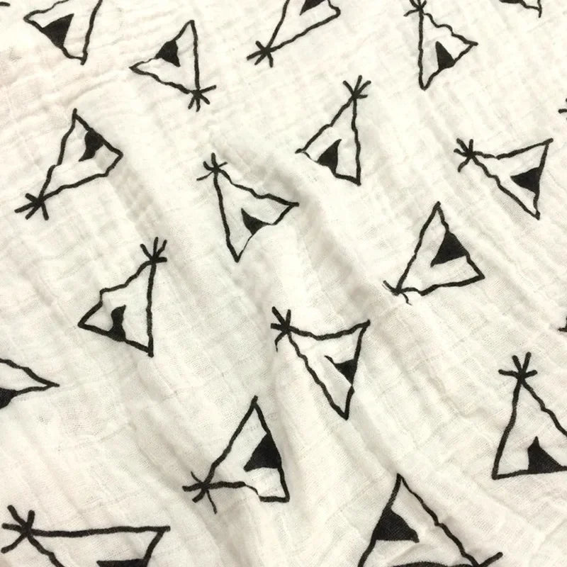 Un gros plan de la Couverture en Mousseline de Coton pour Bébé de BABY PREMA avec un motif monochrome de figures triangulaires abstraites ou stylisées qui ressemblent à des nœuds papillon ou à des mouchoirs, idéal pour les accessoires bébé.