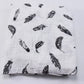 Un tissu doux au motif imprimé plumes monochromes, légèrement froissé, suggérant une texture douillette pour BABY PREMA Couverture en Mousseline de Coton pour Bébé.