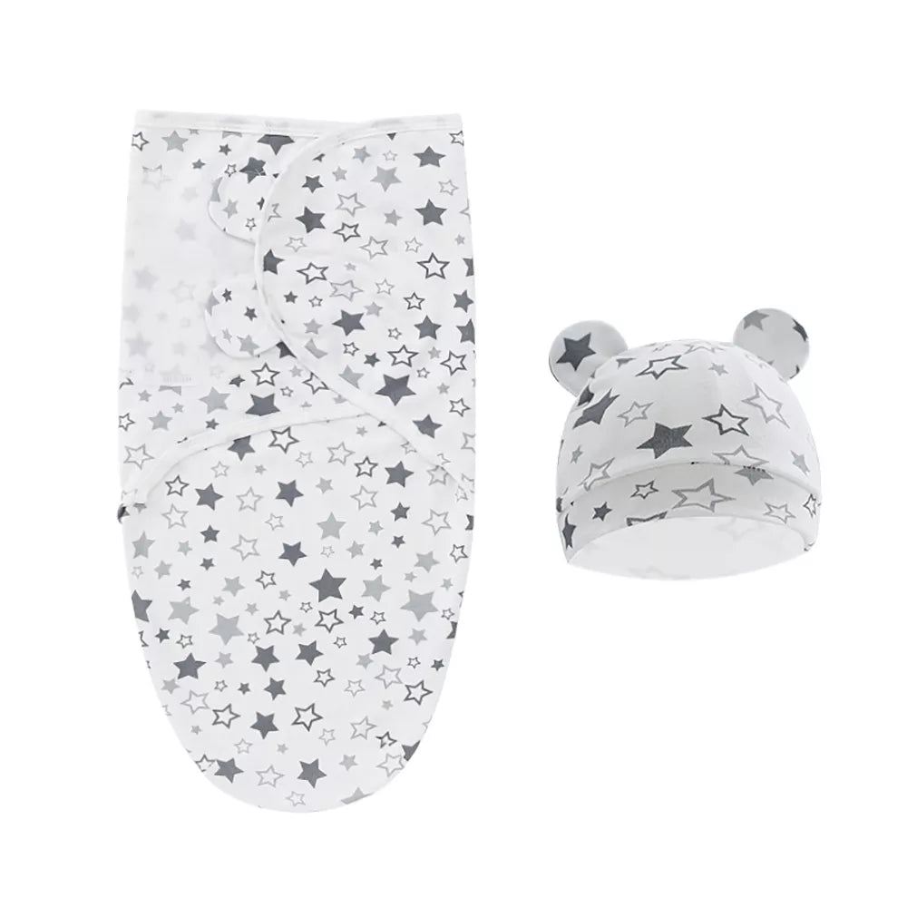 Un ensemble d'accessoires bébé comprenant une couverture bébé emmaillotage BABY PREMA blanche avec un motif d'étoiles grises et un bonnet assorti avec de m