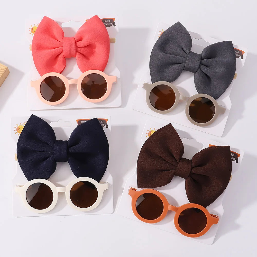 Quatre ensembles de Set d'Accessoires Bébé | Lunettes de Cheveux pour Bébé de BABY PREMA avec des nœuds de différentes couleurs (rose, gris, bleu marine et marron) affichés sur fond blanc.