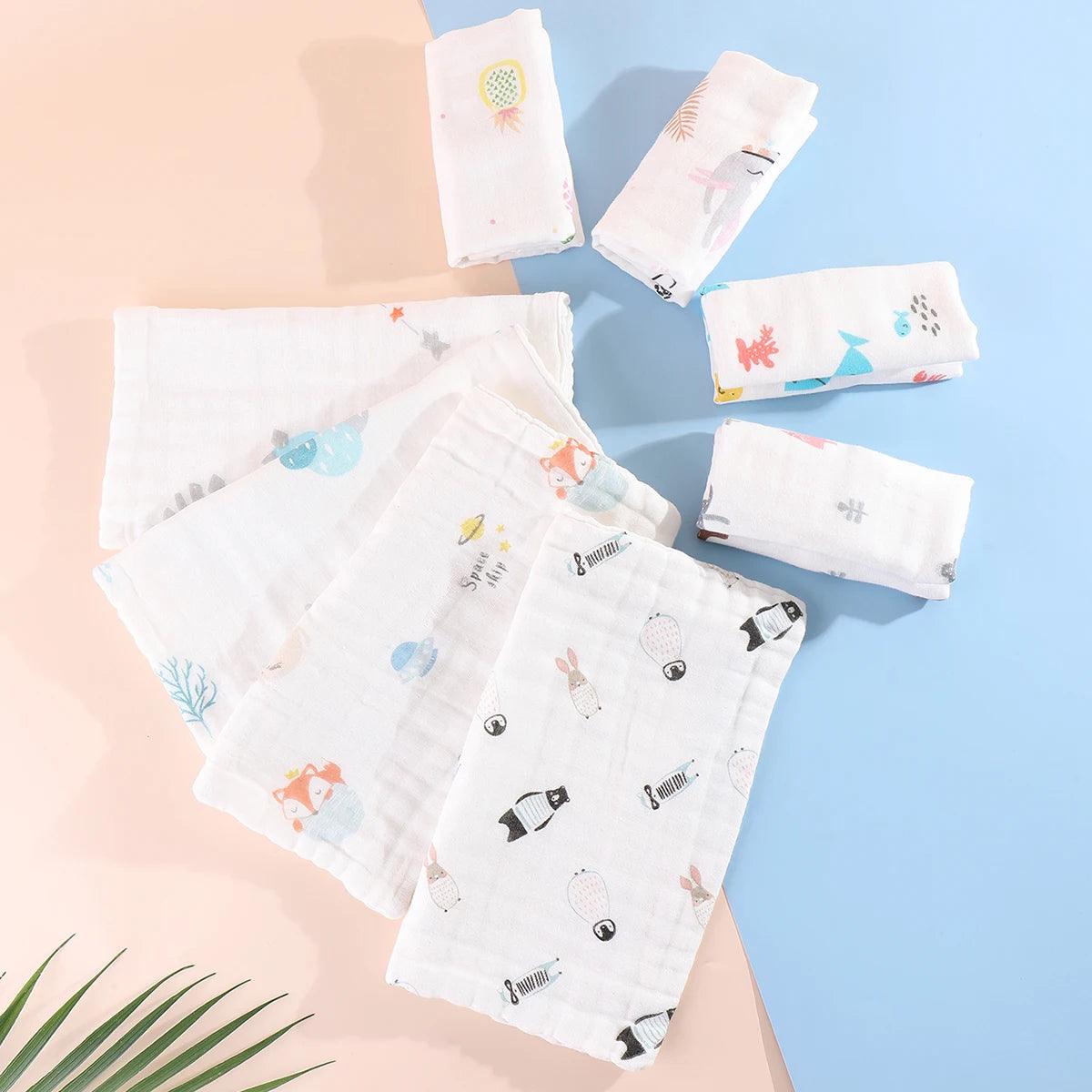 Une collection de 5 langes en mousseline douce à motifs Baby-Prema, disposés de manière créative sur un fond bleu pastel et rose, avec une touche de verdure pour un look frais, parfait pour l'hygiène.