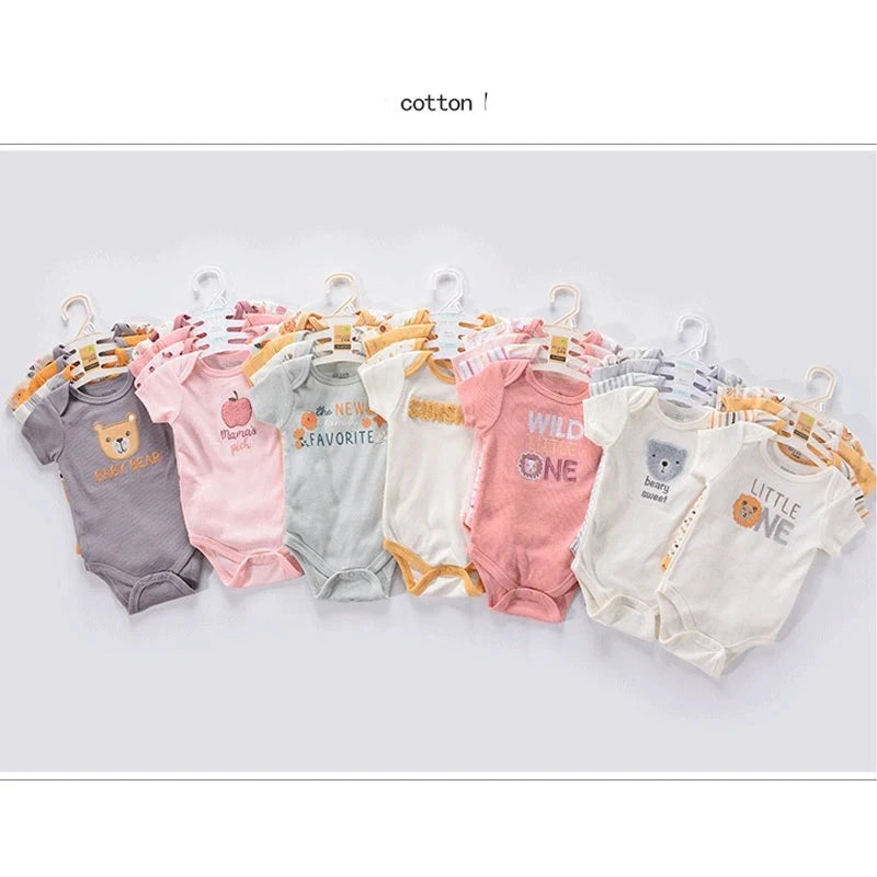 Une sélection de grenouillères pour bébé de différentes couleurs et motifs, chacune sur un cintre. Le Lot de 4 Bodies Coton Bébé Couleurs été de BABY PREMA est fabriqué en coton doux et présente différents imprimés et textes, tels que des animaux et des phrases comme « Wild One » et « Little One », parfaits pour les aventures estivales.