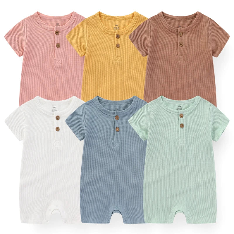 Six BABY PREMA Barboteuses en Coton 2 Pièces | De 0 à 24 Mois, ou barboteuses à manches courtes, sont disposées en deux rangées de trois. Les barboteuses sont aux couleurs pastel : rose, jaune, marron, blanc, bleu et vert. Chacun présente une patte à trois boutons sur le devant et de jolis motifs de dessins animés.