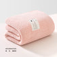 Une couverture tricotée rose douce soigneusement pliée sur une surface de couleur claire avec une étiquette BABY PREMA qui comprend les informations produit Lange Couverture Bébé 105X105cm, dégageant une sensation de chaleur et de confort pour un bébé prématuré.