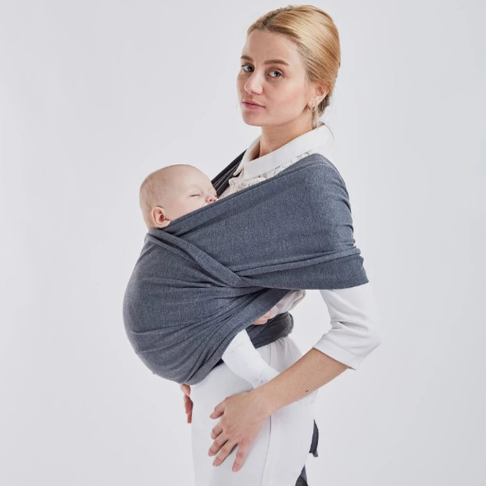 Une maman portant son bébé prématuré dans une Echarpe de Portage de Bébé Confortable & Doux BABY PREMA sur fond uni.