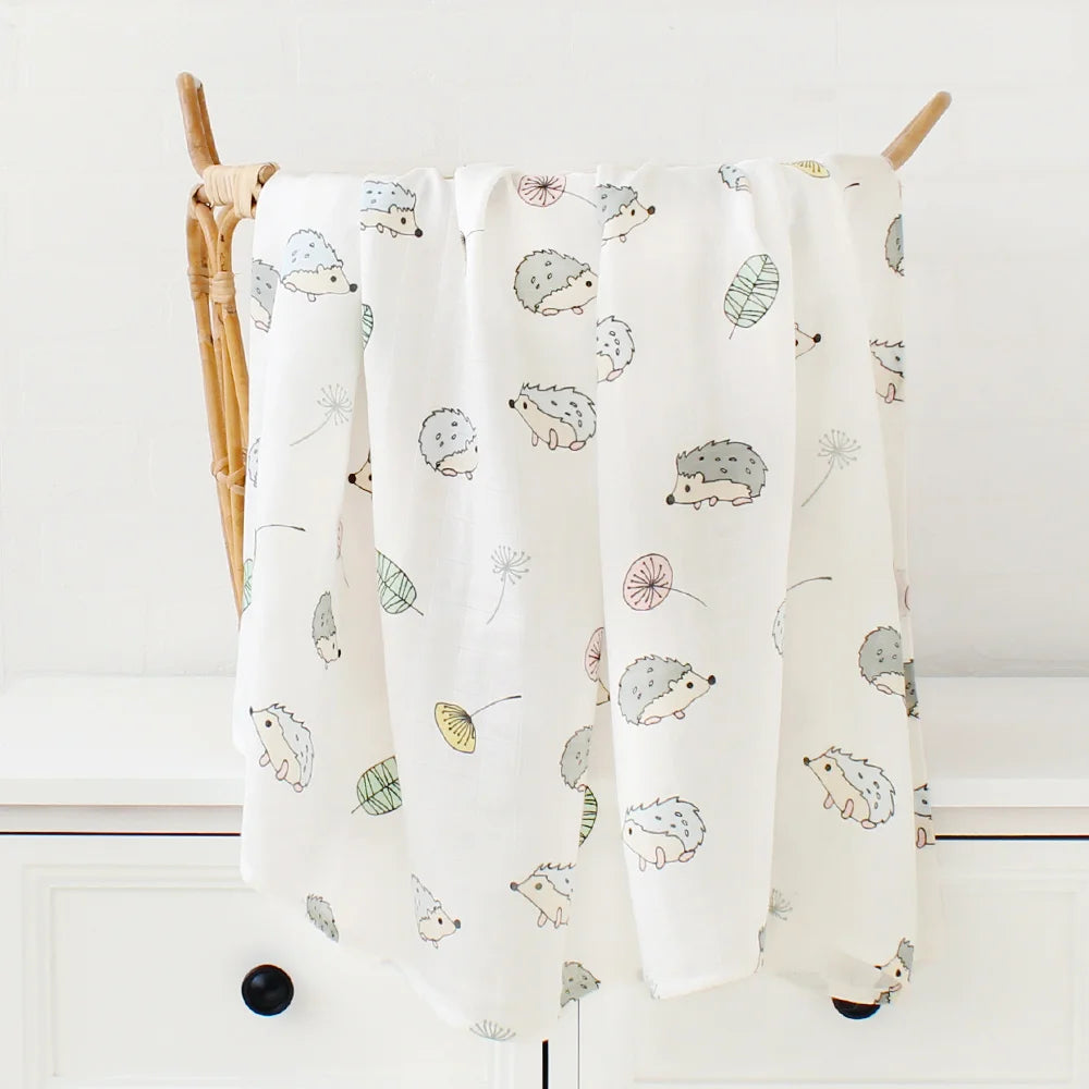 Un torchon de cuisine fantaisiste Lange Bébé en Bambou & Coton avec un joli motif de hérisson et de feuilles drapé sur un rail en bois par BABY PREMA.