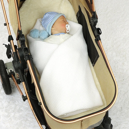 Une poupée BABY PREMA au sommeil paisible, enveloppée dans une couverture Blanche Bébé Tricot Fin 90*70 cm et allongée dans une poussette, avec un bonnet à rayures bleues, une tétine et les accessoires indispensables pour bébé.
