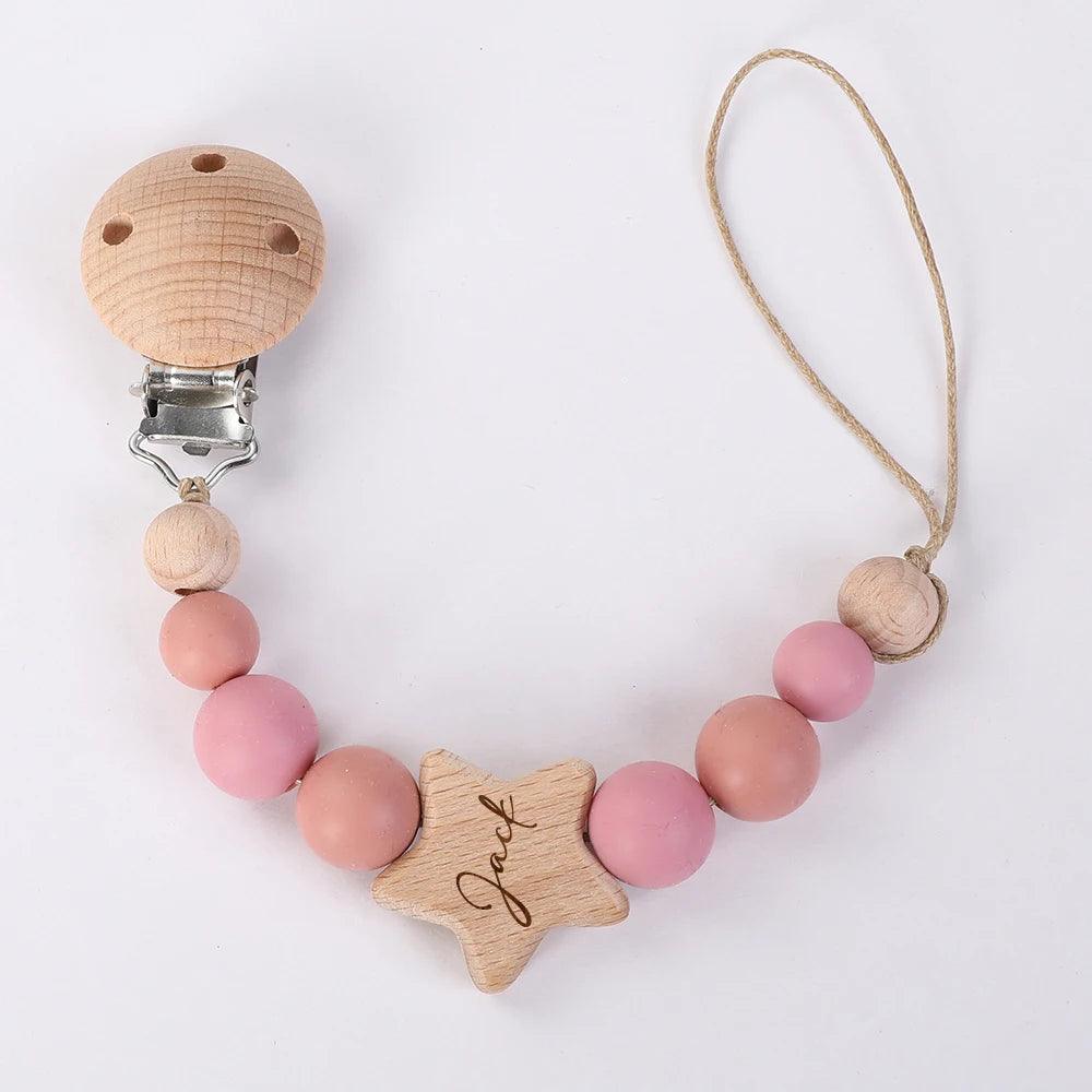 Un accessoire bébé : un Attache Sucette Bébé Personnalisé en bois avec des perles roses et un clip en forme d'étoile, personnalisé avec le nom "jack" de la marque BABY-PREMA.