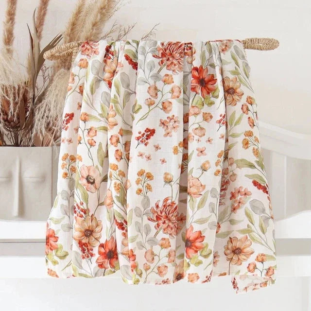 Les couvertures en bambou bébé à motifs floraux de BABY PREMA se drapent gracieusement, affichant une gamme de fleurs et de feuilles aux tons chauds, intégrant un charme douillet et vintage aux accessoires essentiels pour bébé.