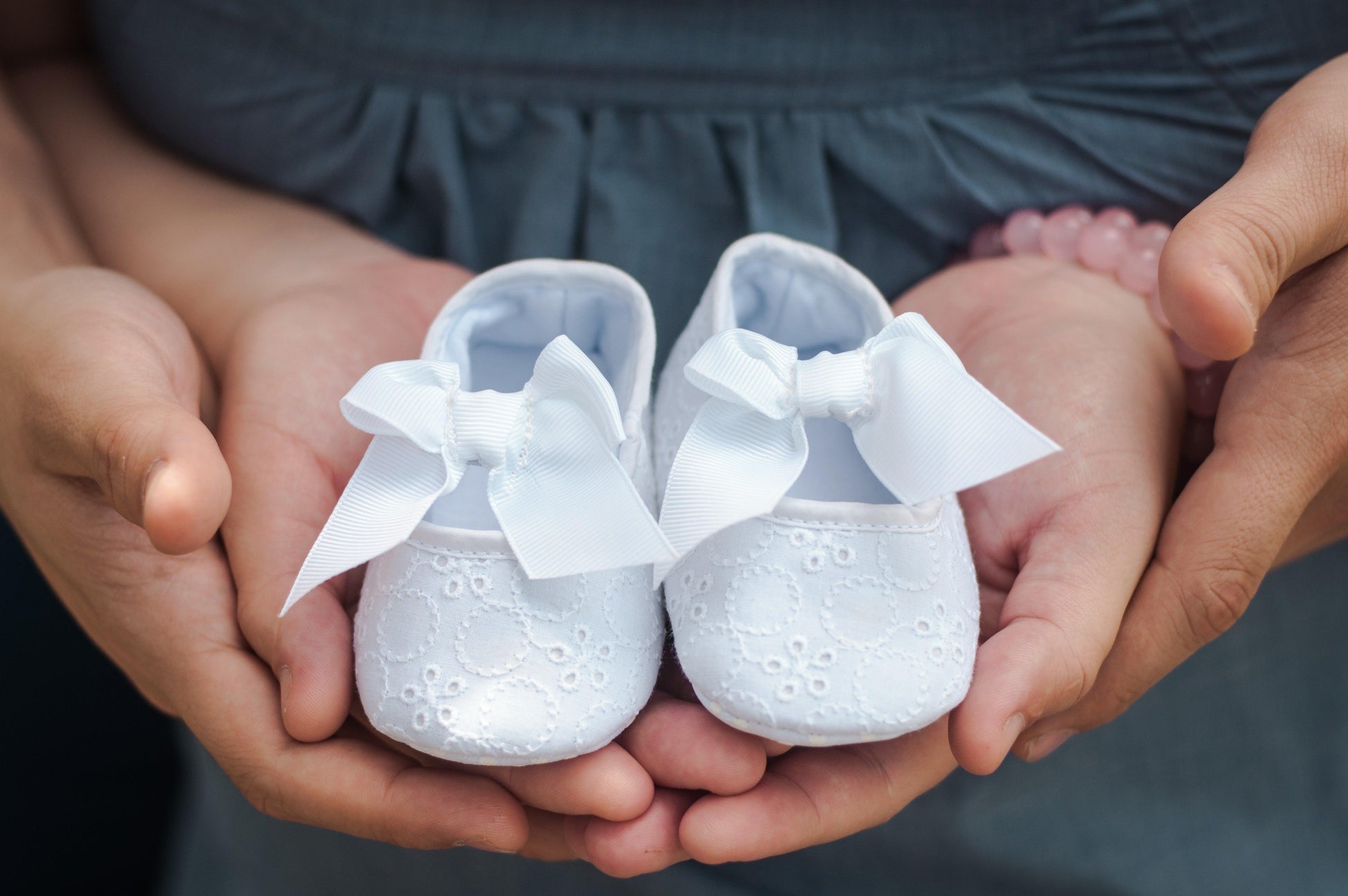 Une paire de mains tient délicatement une carte cadeau naissance BABY-PREMA, symbolisant l'anticipation d'une nouvelle arrivée